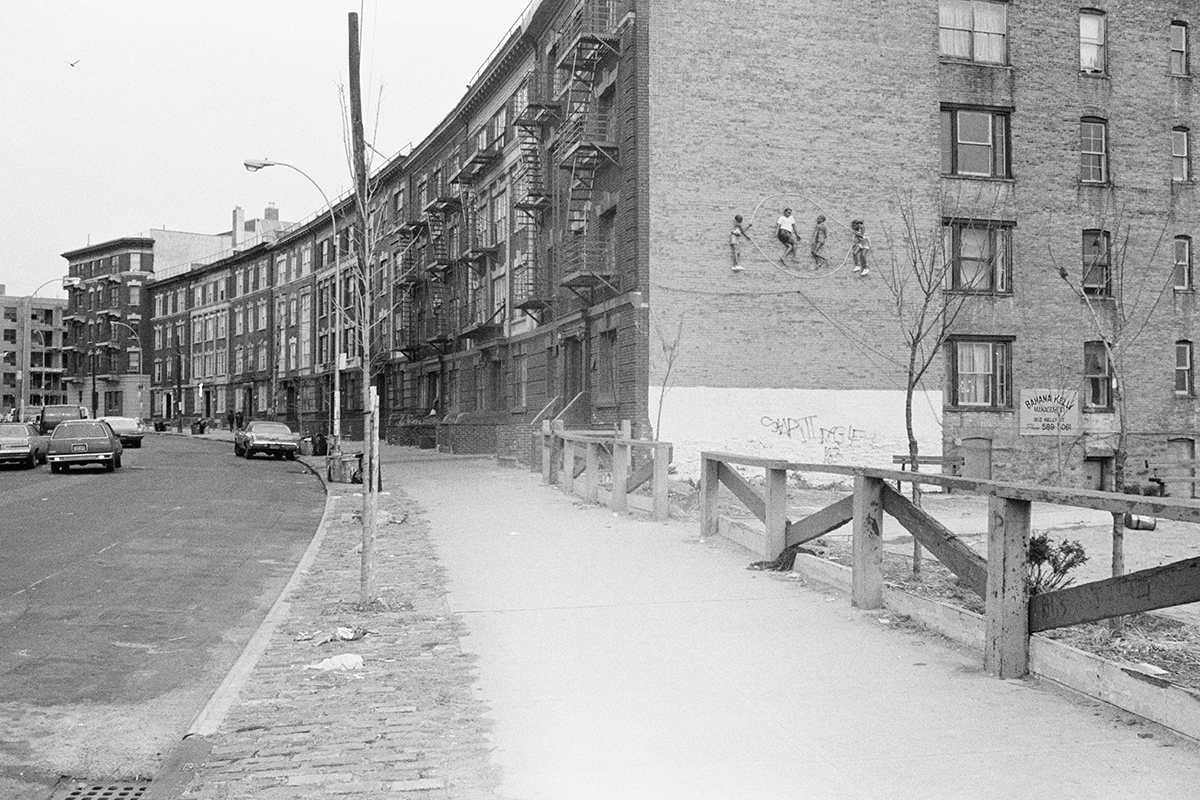 A sculpture of four girls jumping rope, installed on the side of a building