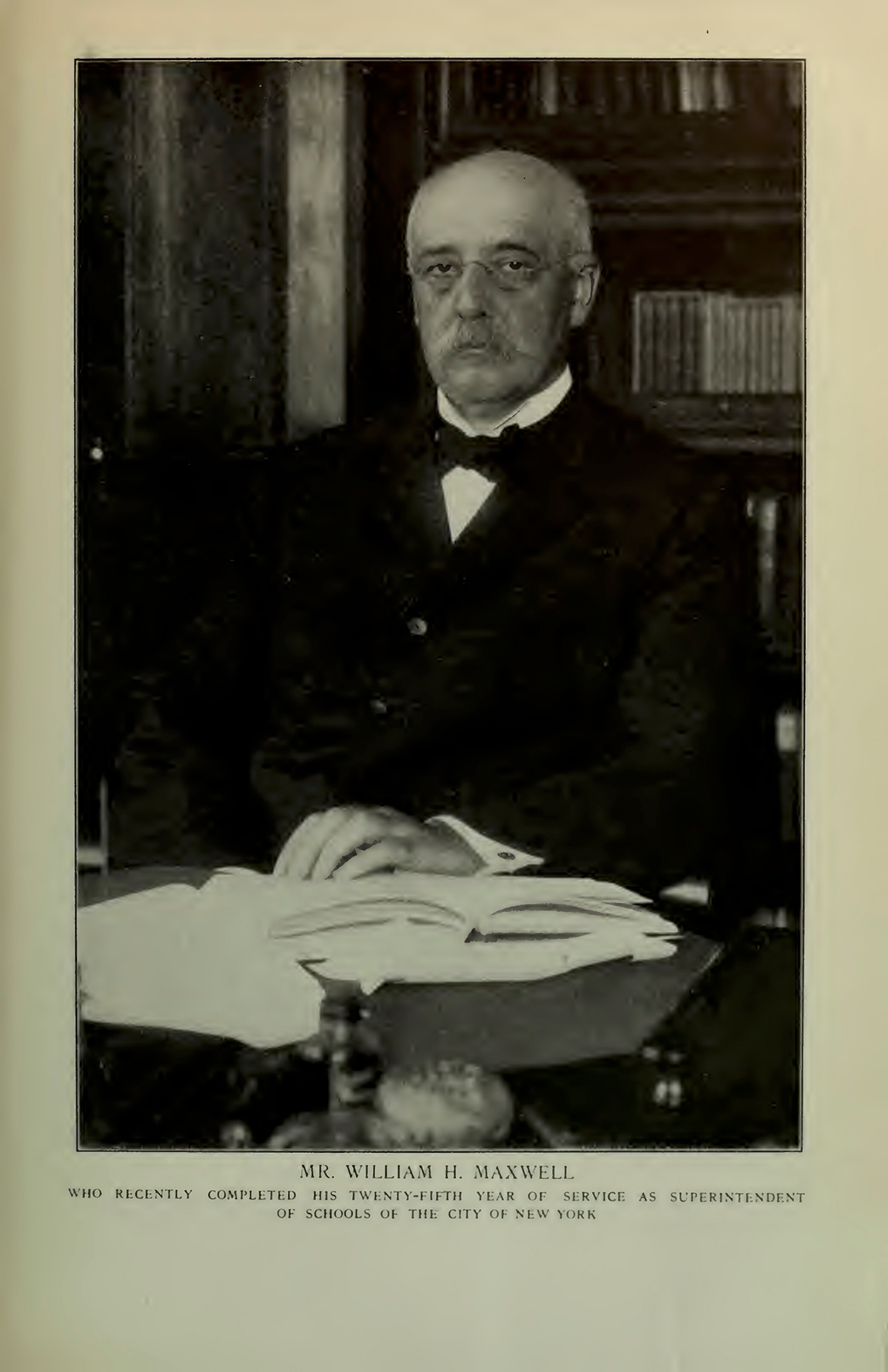 An older bald white man with a moustache and glasses poses in his office. The caption reads "Mr. William H. Maxwell who recently completed his twenty-fifth year of service as superintendent of schools of the City of New York."